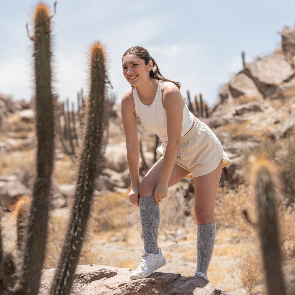 Hiker in the desert pulling up grey baby alpaca over-the-calf socks